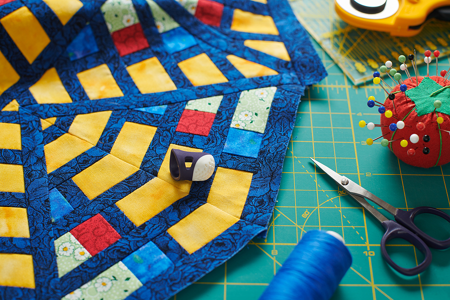 Fragment of a quilt, surrounded by tools for quilting